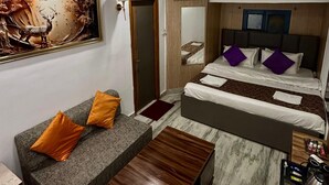 A hotel room with a bed, a sofa, a coffee table, and a bathroom visible through an open door. - Moustache Hostel Rishikesh (Rishikesh)