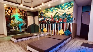 A room with a bed, a bench, and a mural on the wall. - Moustache Hostel Rishikesh (Rishikesh)