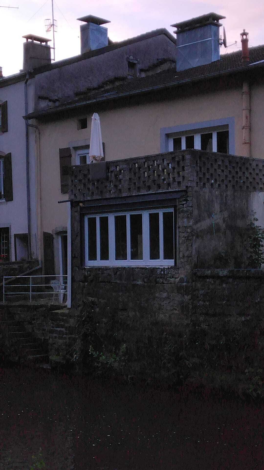 A building with a brick facade, a window with white frames, and a satellite dish on the roof.