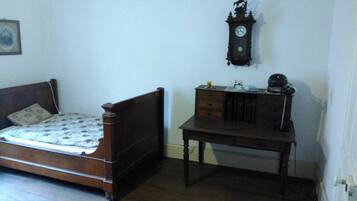 Ein Schlafzimmer mit einem hölzernen Bett, einem Schminktisch und einer Wanduhr.