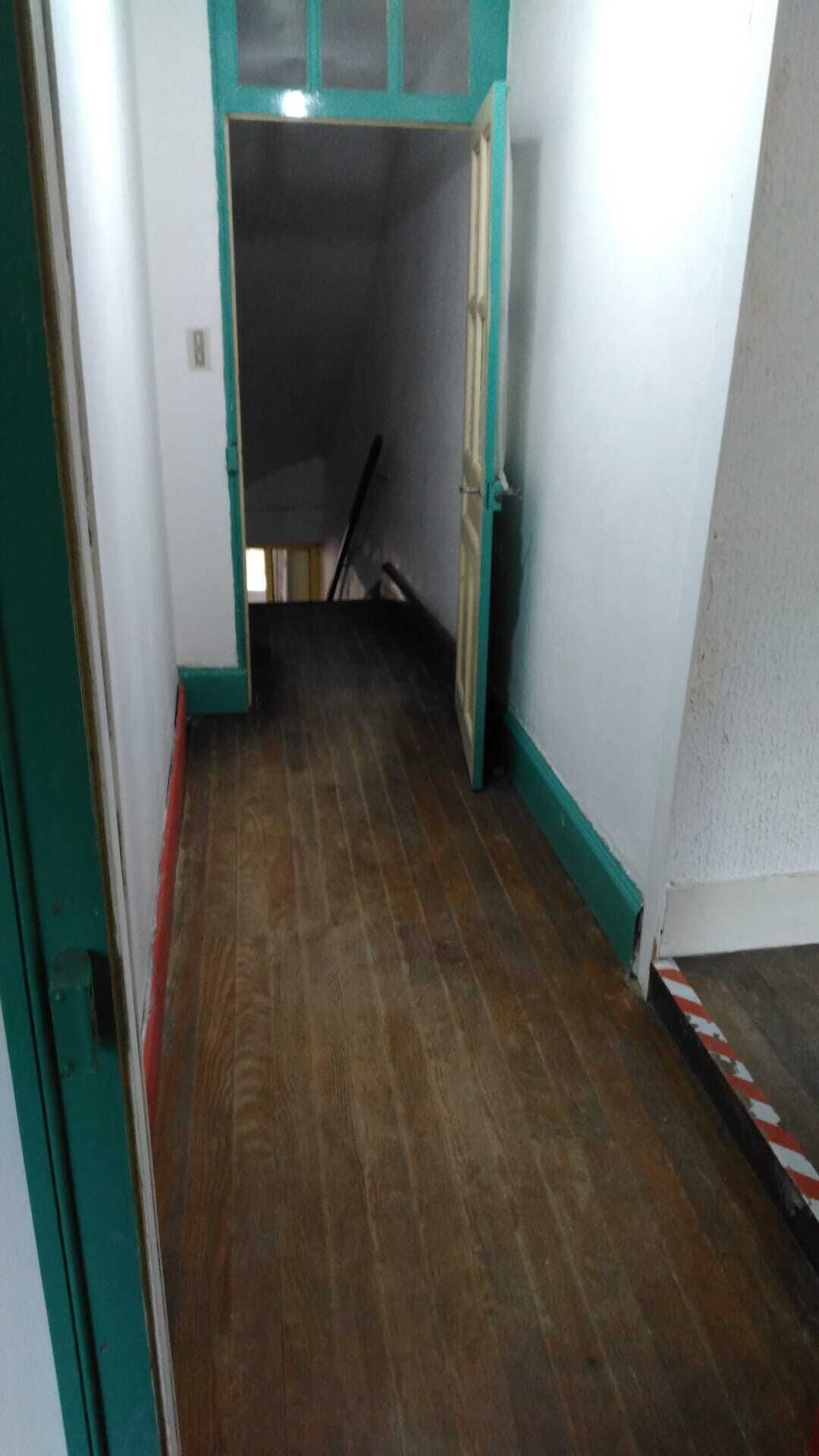 En smal gang med trægulv og turkis detaljer.