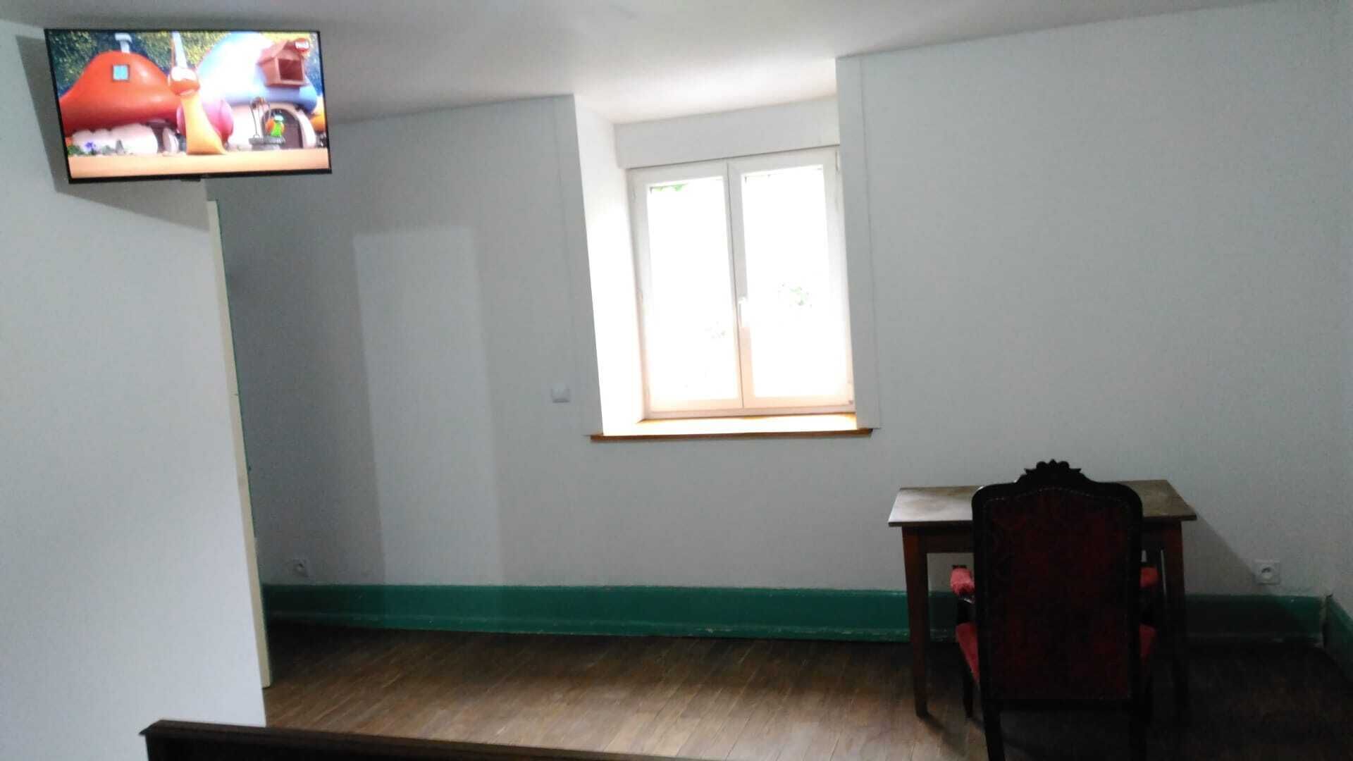 Una habitación con piso de madera, una ventana con persianas, un escritorio pequeño y una silla.