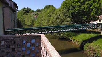 A green bridge over a river with a building on one side and trees in the background.