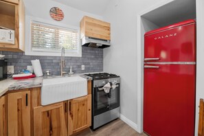 Enjoy cooking in this well-equipped kitchen with a gas stove, oven, refrigerator, and wooden cabinets.
