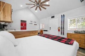 Relax in a spacious room with a loft-style ceiling, a large bed, and a desk.