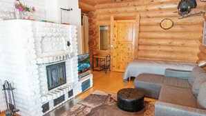 A log cabin interior with a stone fireplace, a sofa set, and a television.