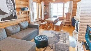A cozy log cabin interior with a sofa, ottoman, and a deer rug.