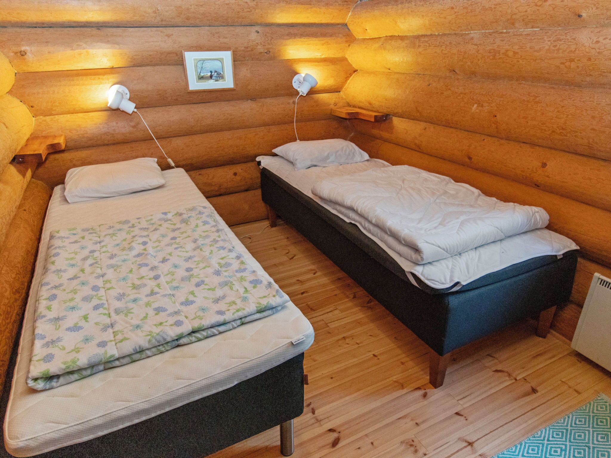 Une chambre confortable, aménagée dans le style d’un chalet, avec deux lits, des murs en bois et un petit tableau accroché au mur.