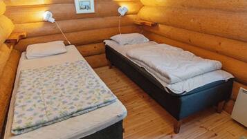 Une chambre confortable, aménagée dans le style d’un chalet, avec deux lits, des murs en bois et un petit tableau accroché au mur.