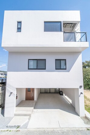 Een modern, tweelaags gebouw met een plat dak, grote ramen en een balkon.