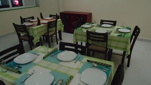 A dining area with tables set for four, each with plates, cutlery, and napkins. - Ajith Safari Lodge (Tissamaharama)