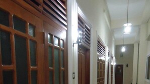 A hallway with wooden doors and a patterned rug. - Ajith Safari Lodge (Tissamaharama)