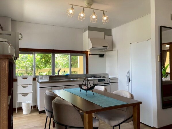 Una cocina moderna con una mesa de comedor, sillas y vistas al exterior con vegetación.