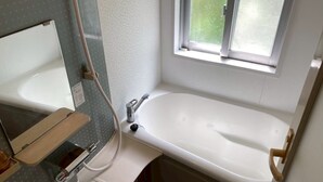 Une petite salle de bain avec une baignoire blanche, un lavabo et une fenêtre.