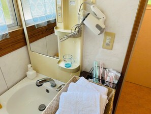 Une salle de bain équipée d’un lavabo, d’un miroir, d’un porte-serviettes et d’articles de toilette.