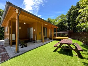 Un bâtiment d’un seul étage doté d’un patio couvert, d’une table de pique-nique et d’un petit espace extérieur aménagé pour s’asseoir.