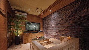 Una habitación de hotel moderna con pared de madera, un televisor de pantalla plana, un sofá y una mesa de centro con una botella de champán.