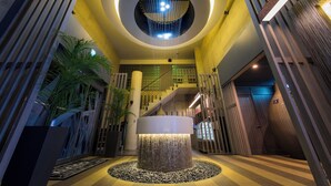 Un vestíbulo moderno con una lámpara circular central, una escalera y una fuente decorativa.
