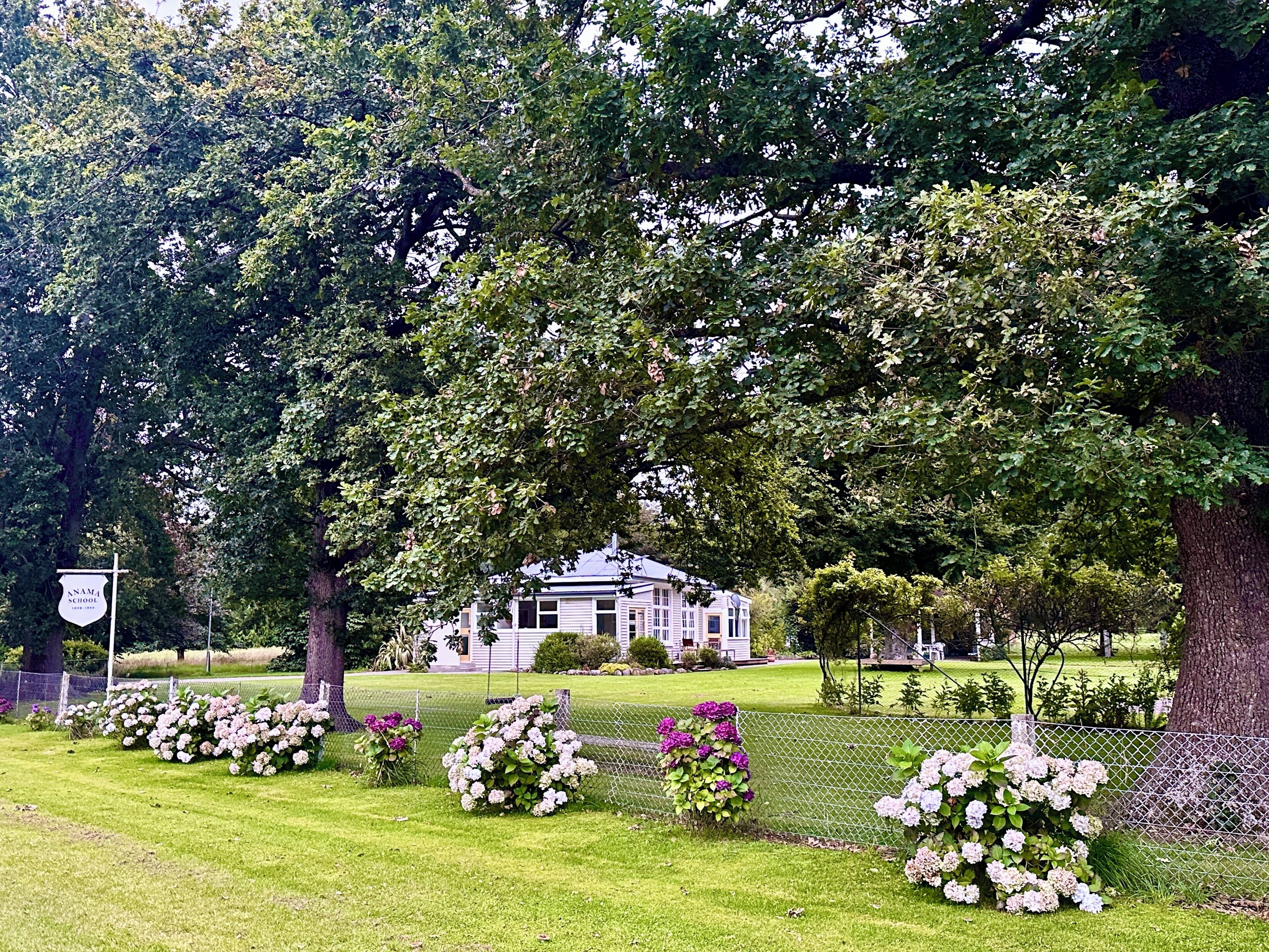 A large, traditional building surrounded by lush greenery and a well-maintained lawn.