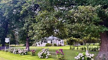 A large, traditional building surrounded by lush greenery and a well-maintained lawn.