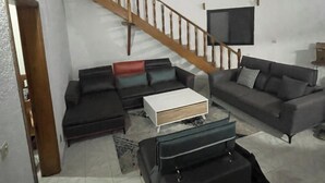 A living room with a staircase, a flat-screen TV, and a sofa set. - Charming 3-bedroom villa with Wifi, AC in lovely Somone near Saly. (Somone)