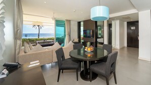 A modern dining area with a glass table, grey upholstered chairs, and a view of the ocean. - Karon Beachfront Apartment 703 (Karon)