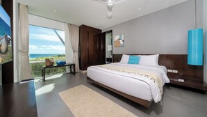 A modern bedroom with a large bed, a ceiling fan, and a view of the ocean. - Karon Beachfront Apartment 703 (Karon)