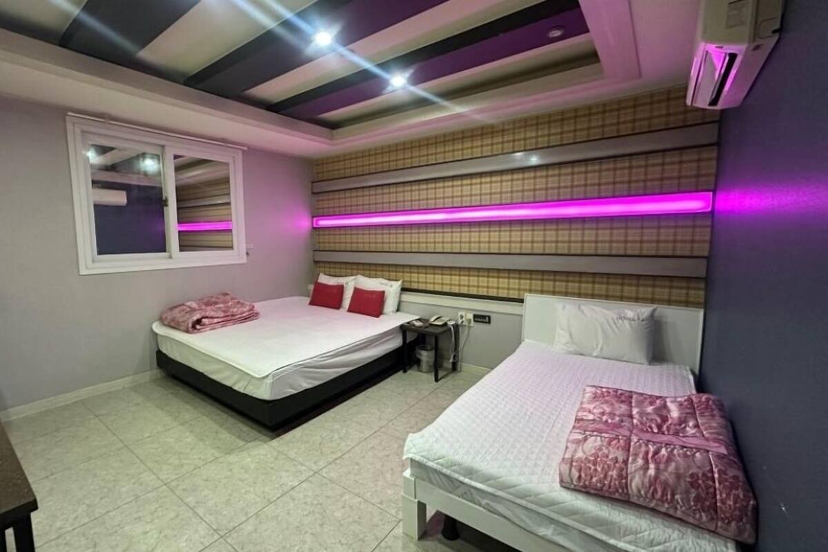 Ein Schlafzimmer mit zwei Betten, einem Fenster, einem Schreibtisch und einer Decke mit Lampen.