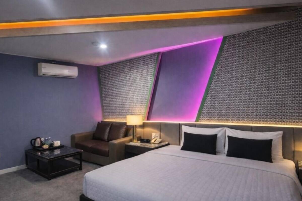 Ein Hotelzimmer mit einem Bett, einem Schreibtisch, einem Stuhl, einer Lampe und einer Klimaanlage.
