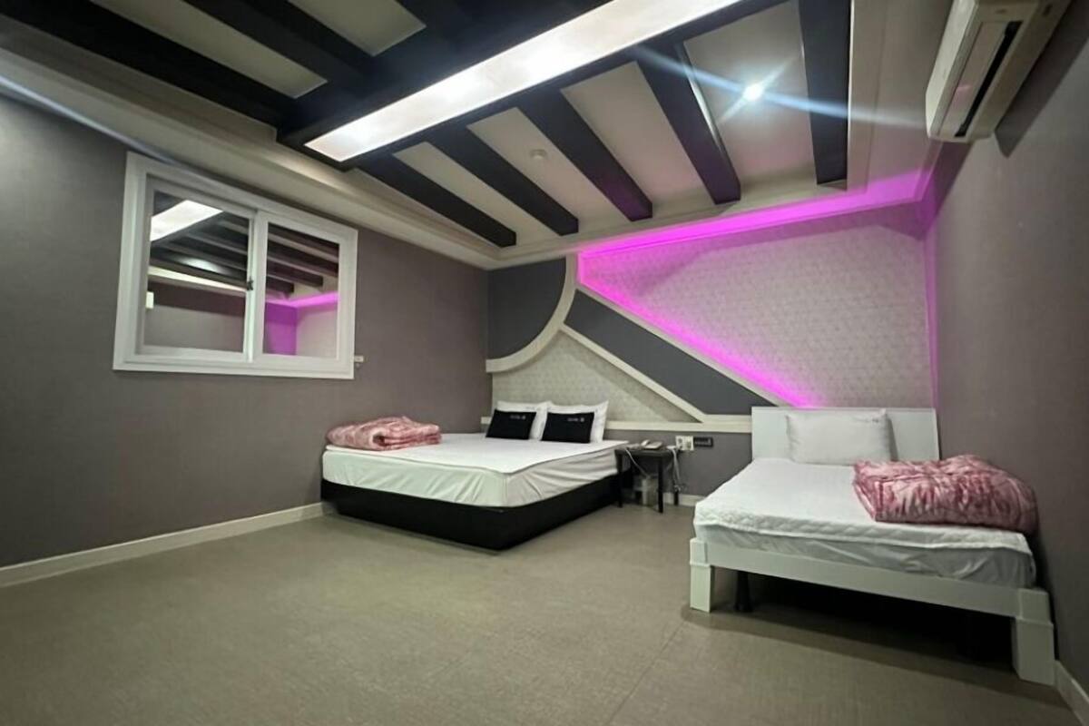 Ein Schlafzimmer mit zwei Betten, einem Fenster und einer Decke mit einem besonderen Design.