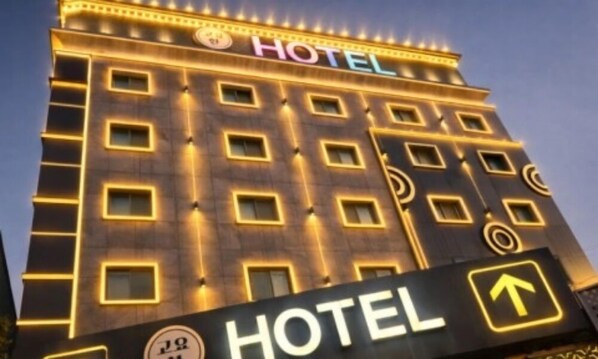 Ein Hotelgebäude mit einem Schild, das den Namen und die Wegweiser zum Eingang zeigt.