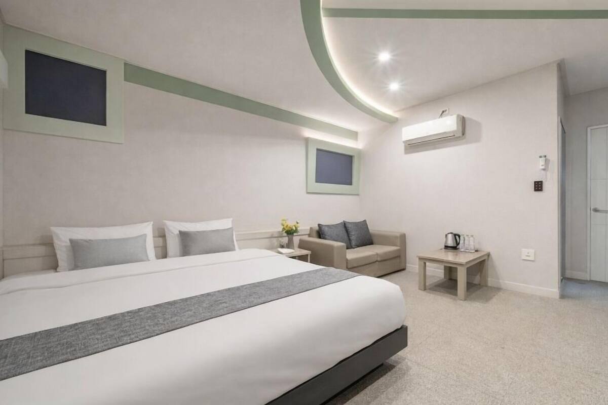 Ein modernes Hotelzimmer mit einem großen Bett, einer Couch, einem kleinen Tisch und einer Tür.