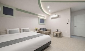 Ein modernes Hotelzimmer mit einem großen Bett, einer Couch, einem kleinen Tisch und einer Tür.