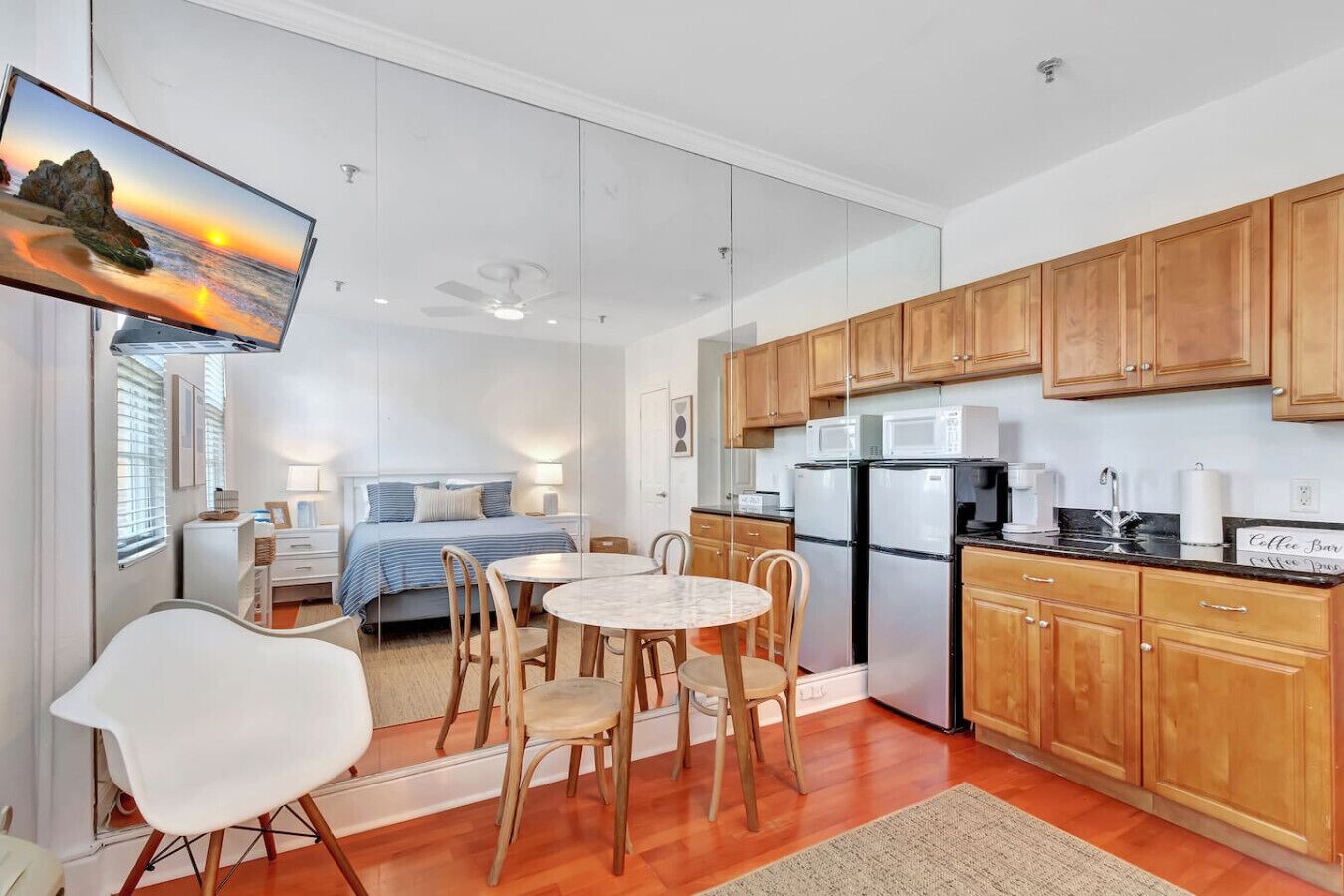 A compact kitchen with wooden cabinets, a refrigerator, a microwave, and a coffee bar sign.