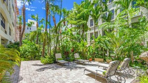 A courtyard with a paved patio, lounge chairs, and a bike rack. - Palm Beach Condo, Poolside Gem! Walk to Beach (Palm Beach)