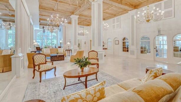 Amplio salón, elegantemente amoblado, con techos altos y candelabros, que incluye sofás, sillones y una mesa de centro.