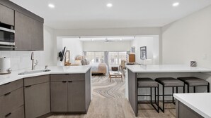 A modern kitchen with a central island, built-in appliances, and a dining area with bar stools. - Palm Beach Island Sleeps 3 Renovated Kitchen Pool (Palm Beach)