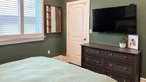 A bedroom with a bed, a dresser, a TV, and a window with blinds. - Silver Lake Gem – 3BR Home with Backyard Oasis (Los Angeles)