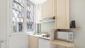 A compact kitchen with a window, a sink, a stove, and a microwave.