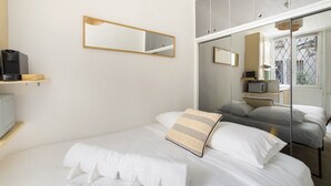 A modern bedroom with a bed, a large mirror, and a wardrobe with a glass door.