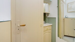 A bathroom with a white door, a mirror, and a green-tiled wall.