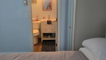 A bedroom with a bed, a door leading to a bathroom, and a visible toilet.