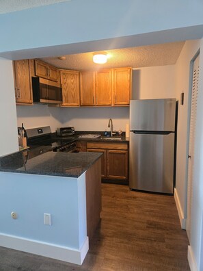 A kitchen with wooden cabinets, a stainless steel refrigerator, and a microwave.