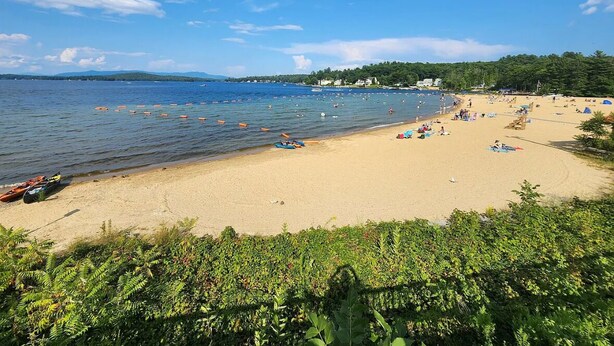 A beach with boats, people, and buildings in the background.
