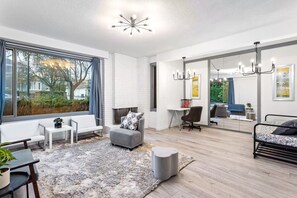 Uma sala de estar moderna com lareira, área de estar e uma grande janela com vista para o exterior.