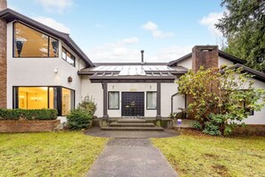 Een huis met twee verdiepingen, een zwarte voordeur, zichtbaar nummer '1052', en een kleine voortuin met een pad naar de ingang.