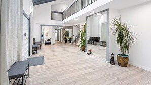 A spacious interior with a high ceiling, a mezzanine level, and a large mirror reflecting the room. - Luxury 5 Bedroom Villa w/Sauna (Vancouver)