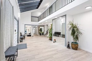 Een ruim interieur met een hoge plafond, een tussenverdieping en een grote spiegel die de ruimte weerspiegelt.