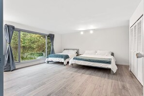 Een slaapkamer met twee bedden, grote ramen en een kledingkast.