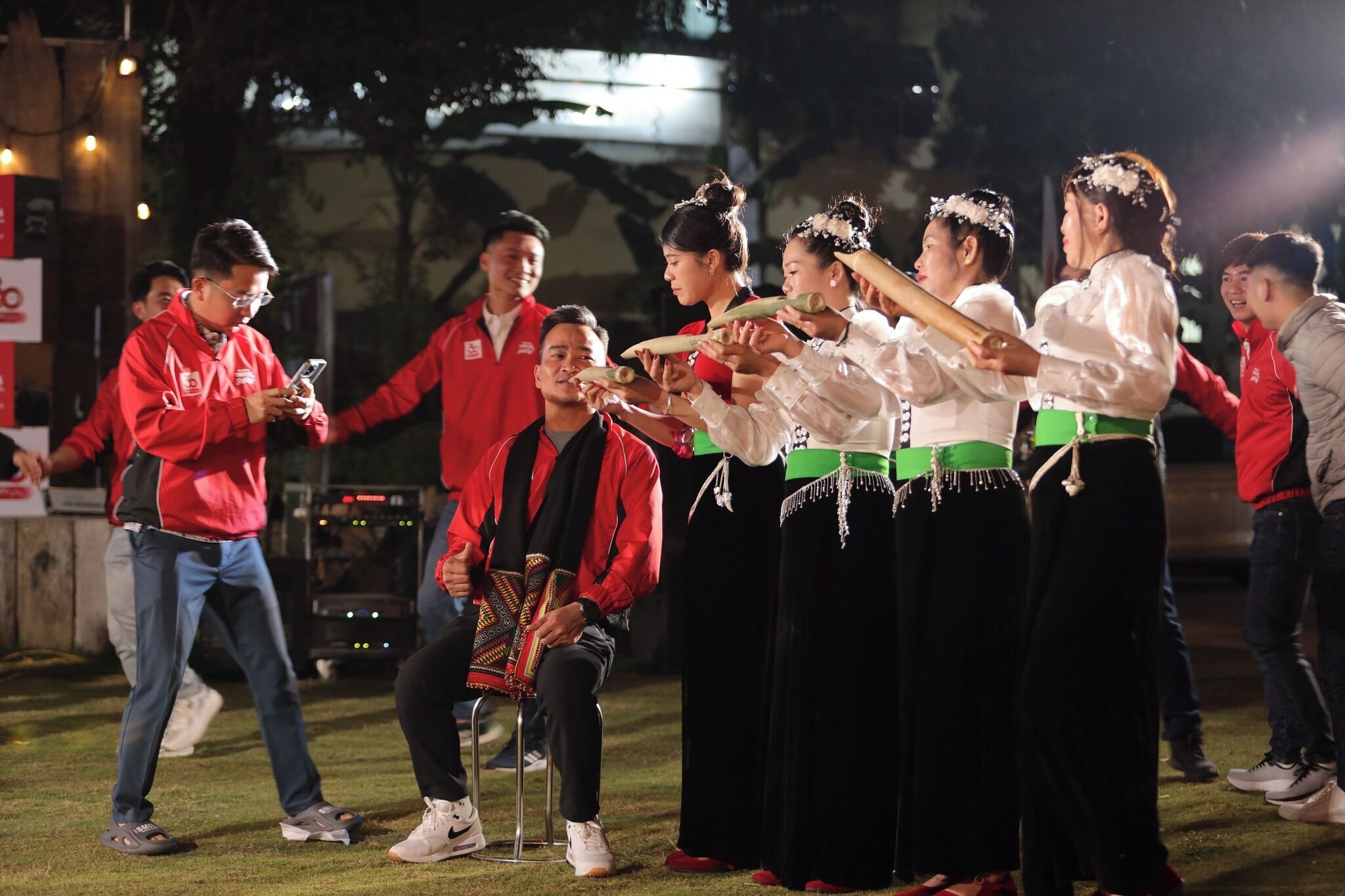 Un groupe de personnes, vêtues de costumes traditionnels, effectue une activité en plein air, de nuit.